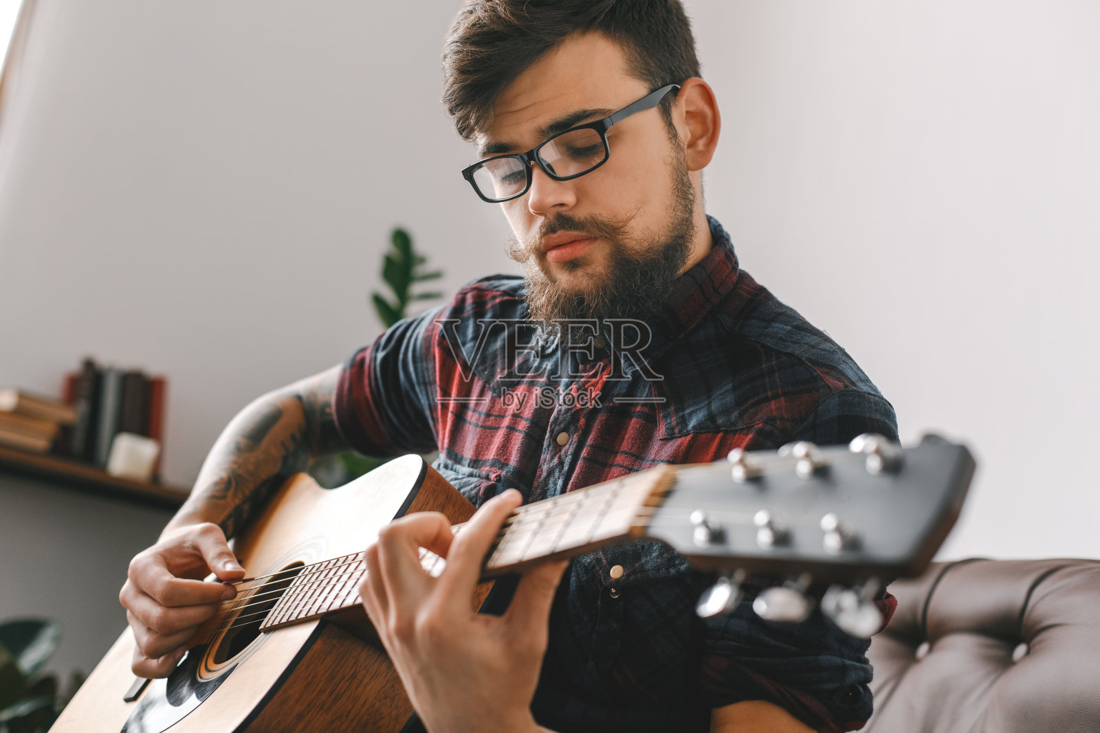 年轻的吉他手潮人在家与吉他坐演奏集中近景照片摄影图片