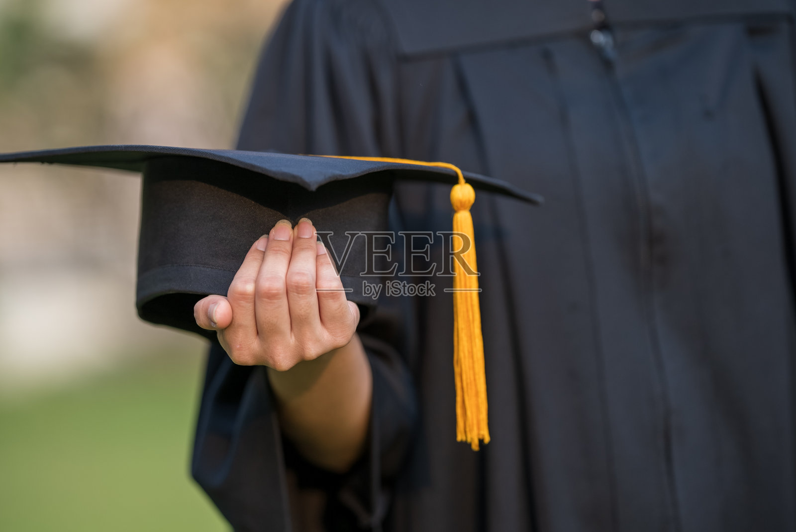 近距离拍摄的大学毕业生持有毕业帽显示和庆祝教育。照片摄影图片