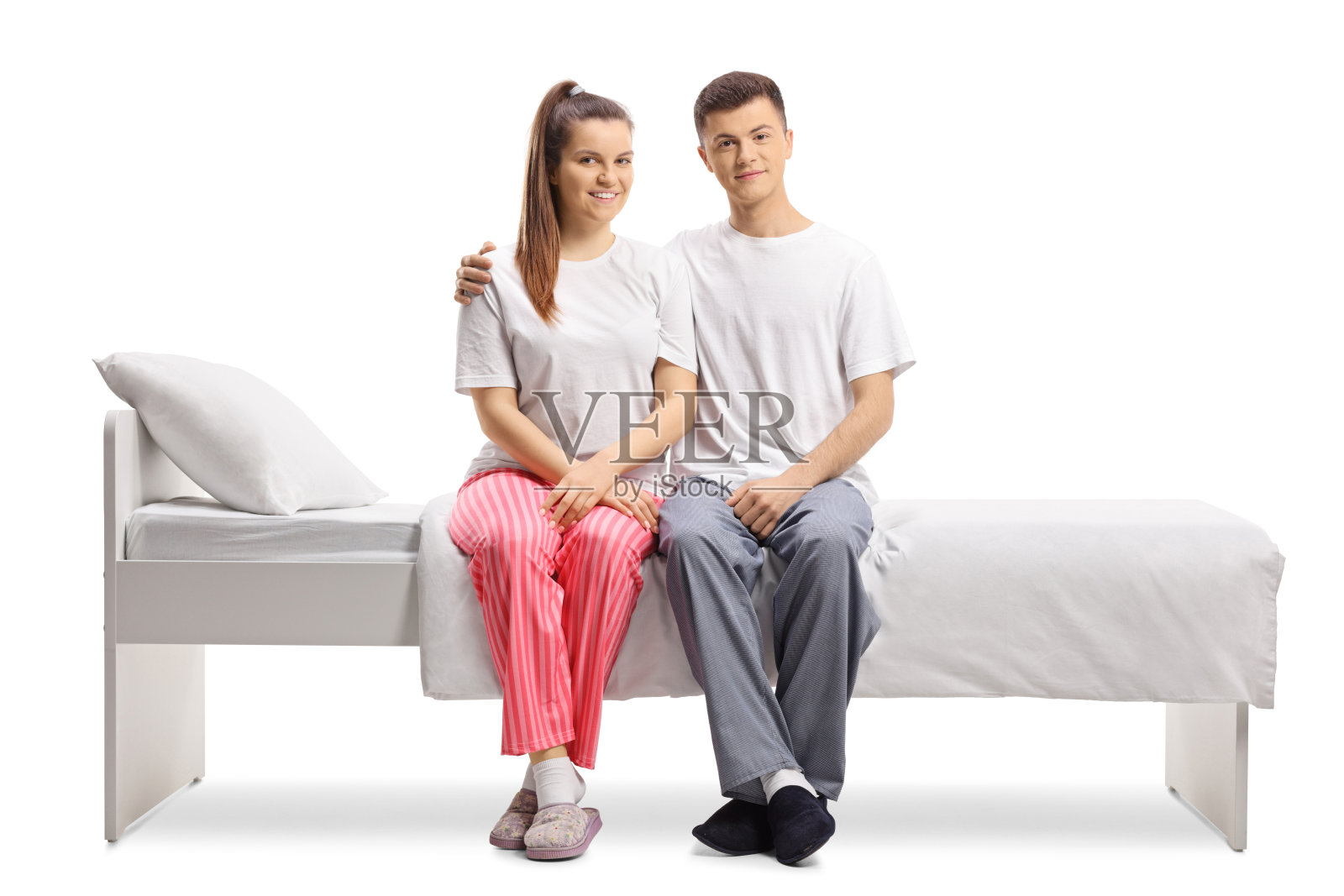 快乐的年轻男女穿着睡衣坐在床上照片摄影图片