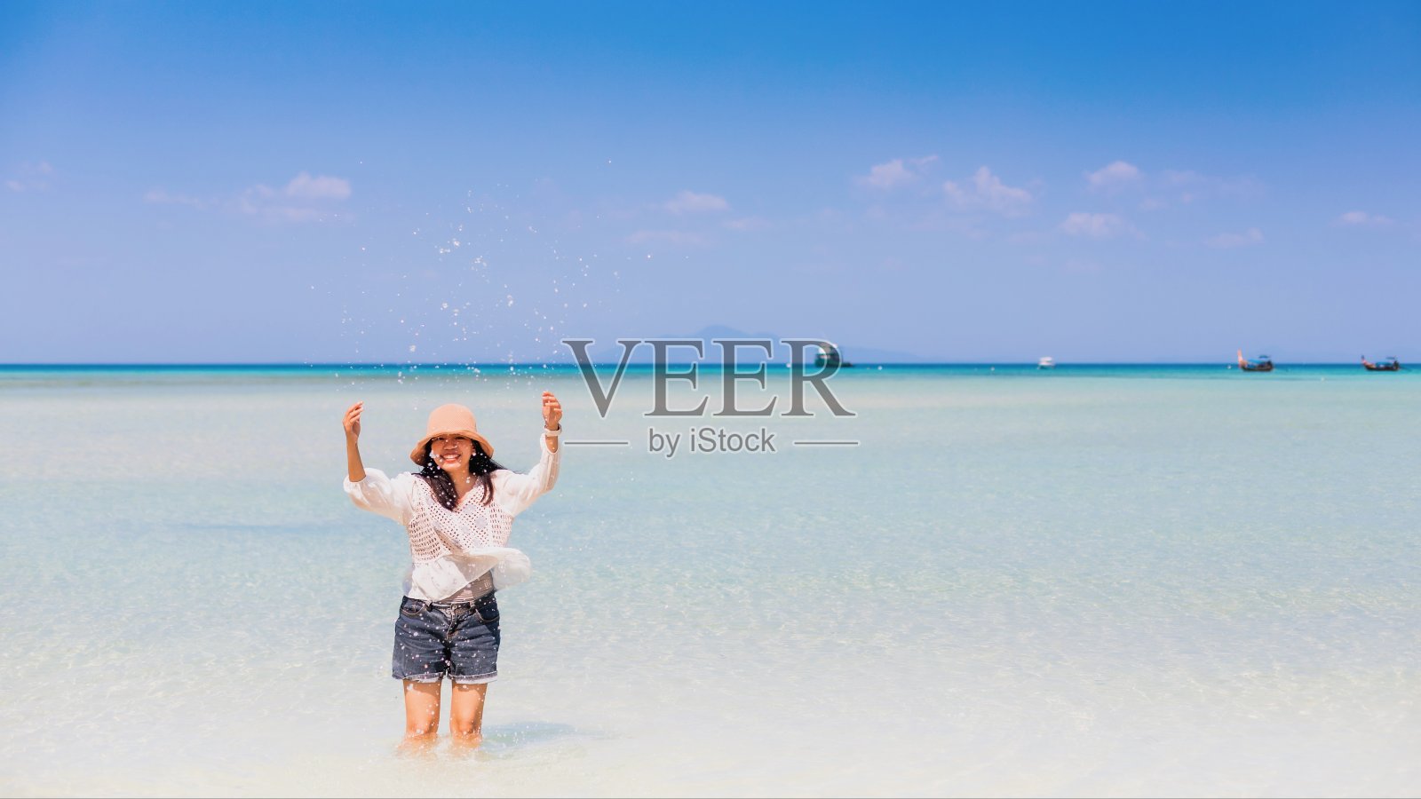 在泰国安达曼海的白色沙滩和岛屿的蓝天上,年轻的女子徒步走向大海。适合夏季旅游休闲。照片摄影图片