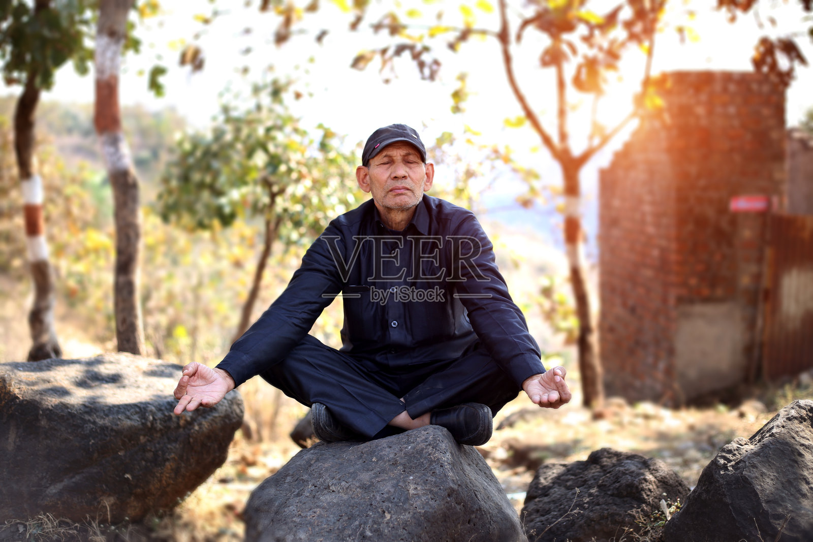 日落时分,坐在岩石上沉思的印度老人照片摄影图片