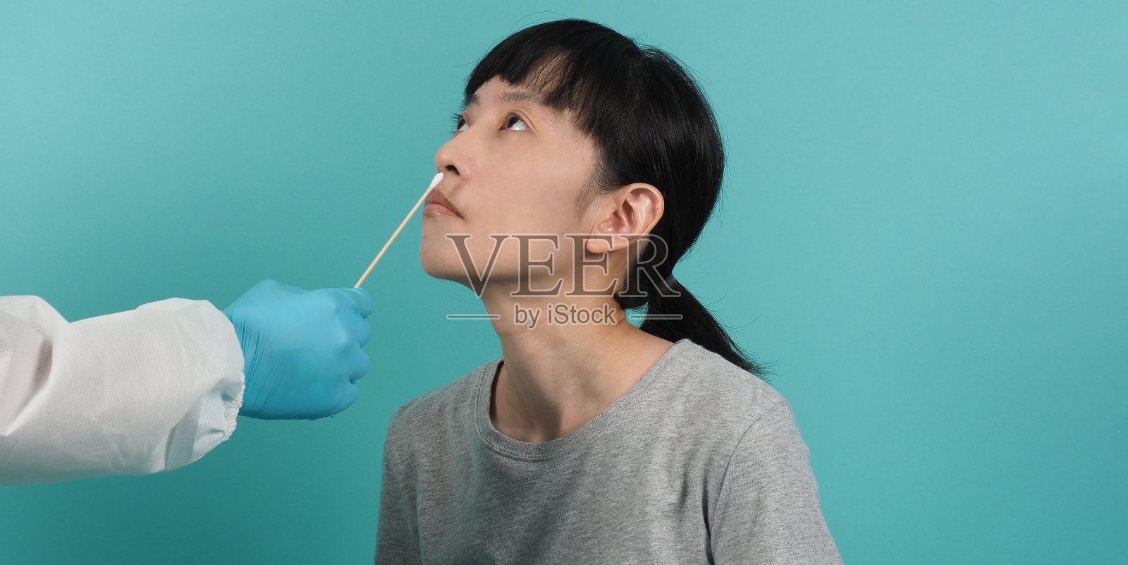 Covid - 19拭子检测。有PCR检测的女性。疫情期间的冠状病毒检测。医生正在取样做病毒检测工作室拍摄和蓝绿色背景。医生在防护服拭子测试。照片摄影图片