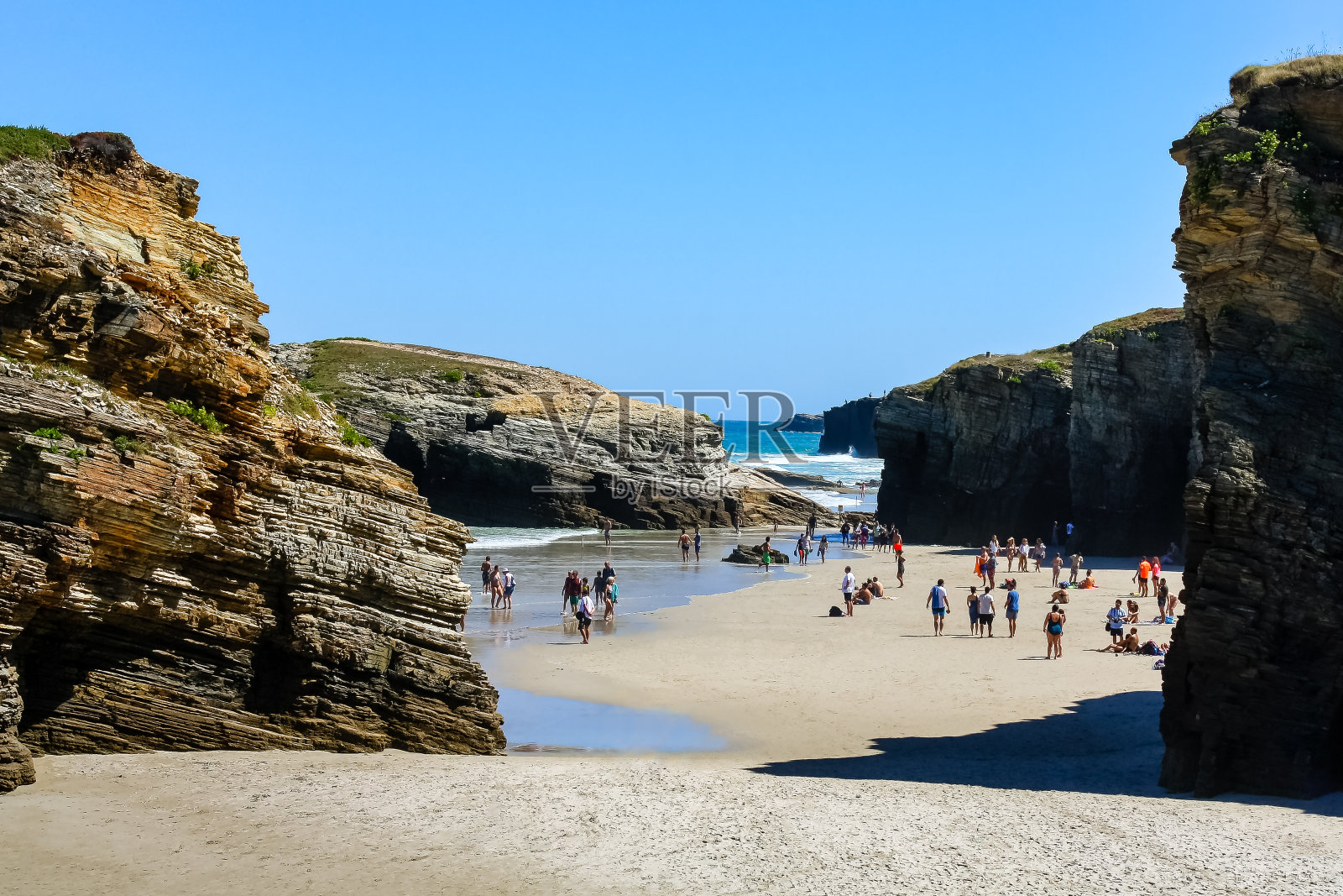 人们在西班牙加利西亚田园诗般的Las Catedrales海滩上晒太阳。照片摄影图片