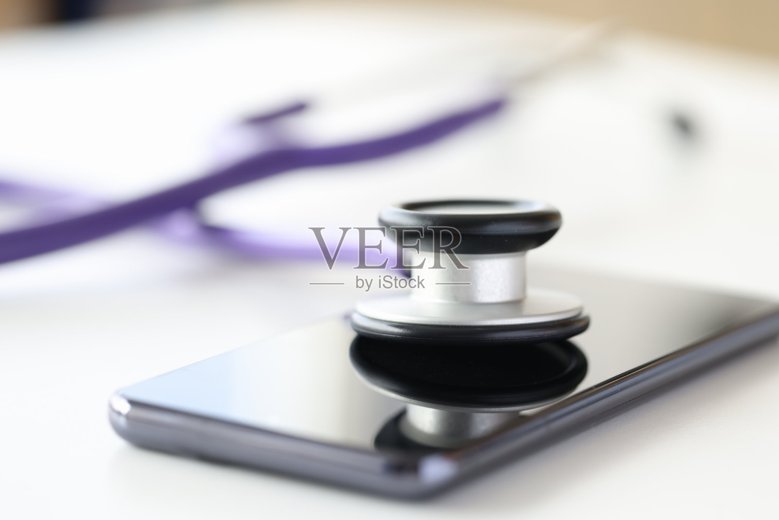 医疗器械听诊器躺在手机屏幕上的特写照片摄影图片