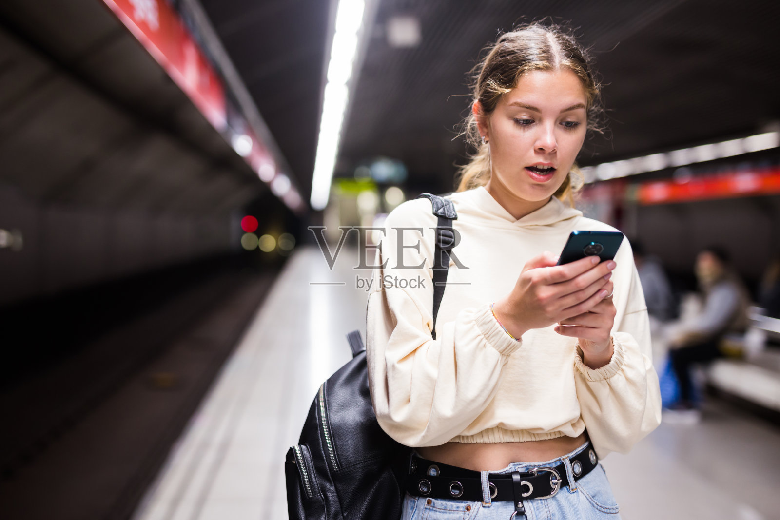 年轻的欧洲女性拿着手机在等地铁照片摄影图片
