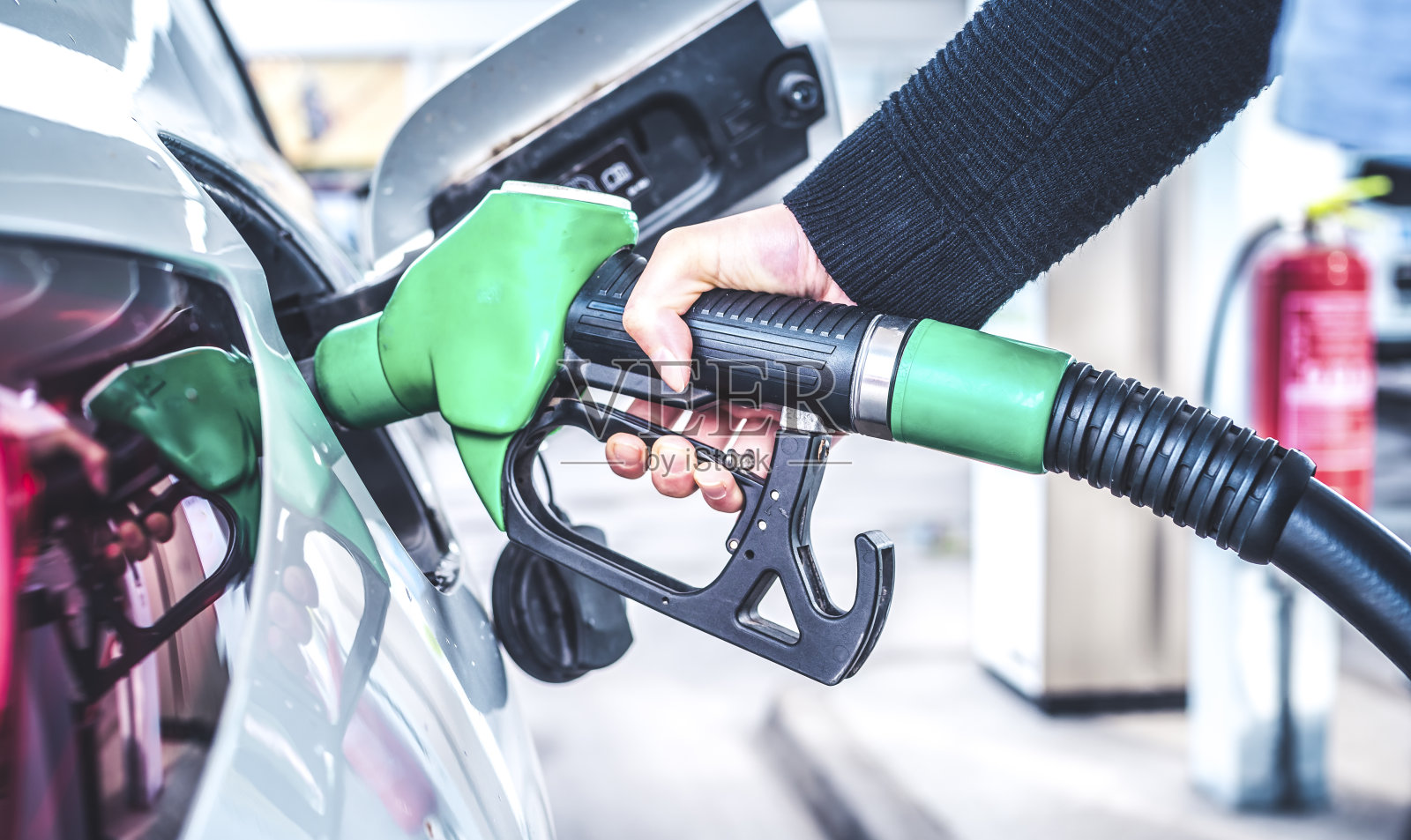 在加油站给车加油的女人。照片摄影图片