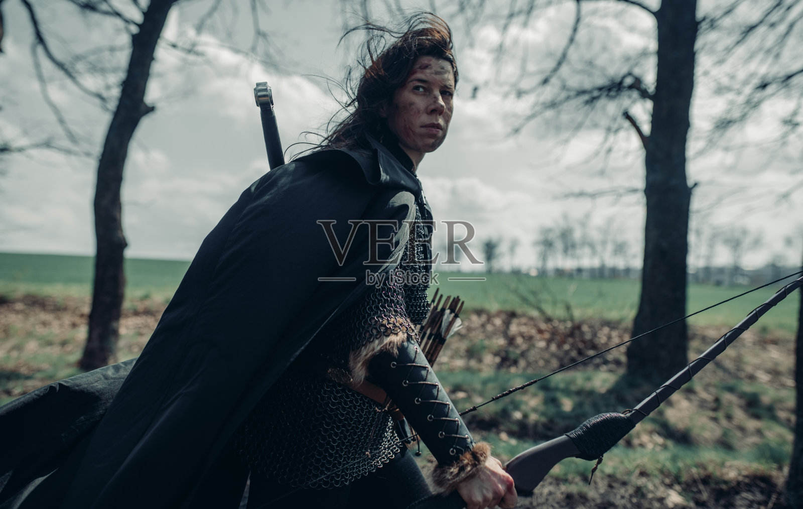 中世纪的女战士弓箭手漫步在森林中。照片摄影图片