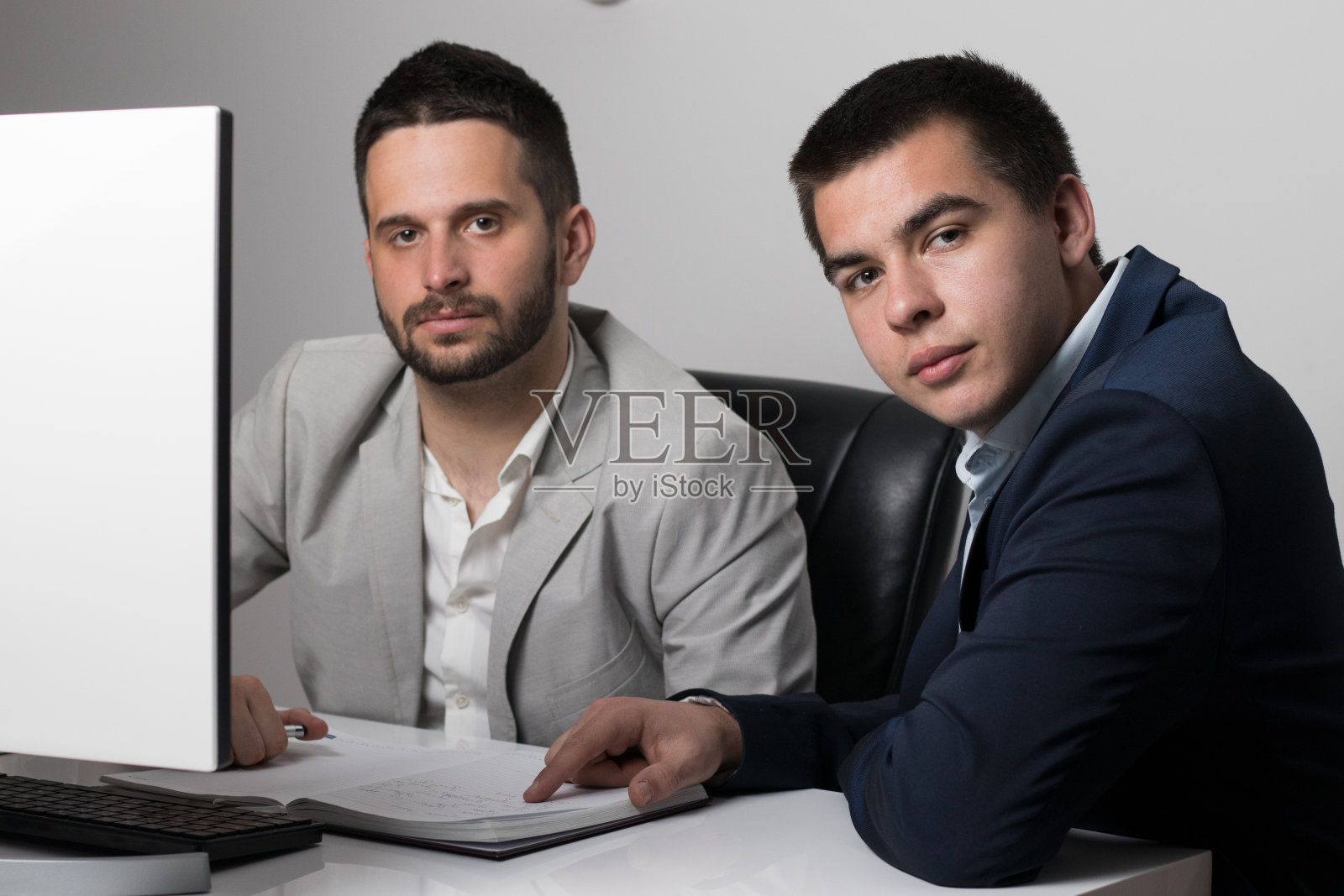 两个英俊的商人一起工作在一个项目坐在桌子上的办公室照片摄影图片