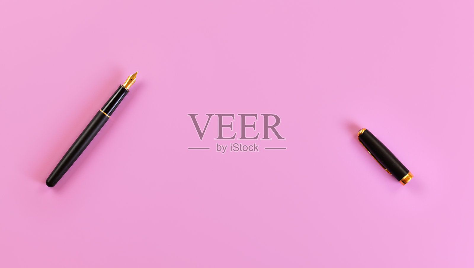 上下视图-黑色的金笔尖钢笔,打开,盖子在右边,粉红色的背景,文字空间。照片摄影图片