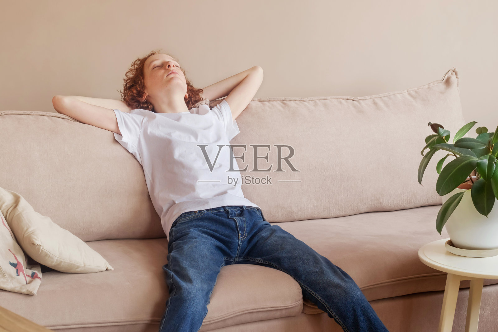 文本的空白。一个少年正坐在沙发上休息。照片摄影图片