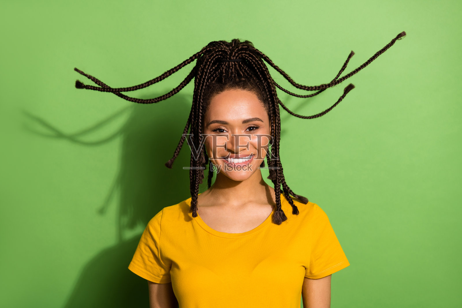 照片漂亮迷人的黑皮肤的女人穿黄色的t恤,风吹头发微笑孤立的绿色背景照片摄影图片