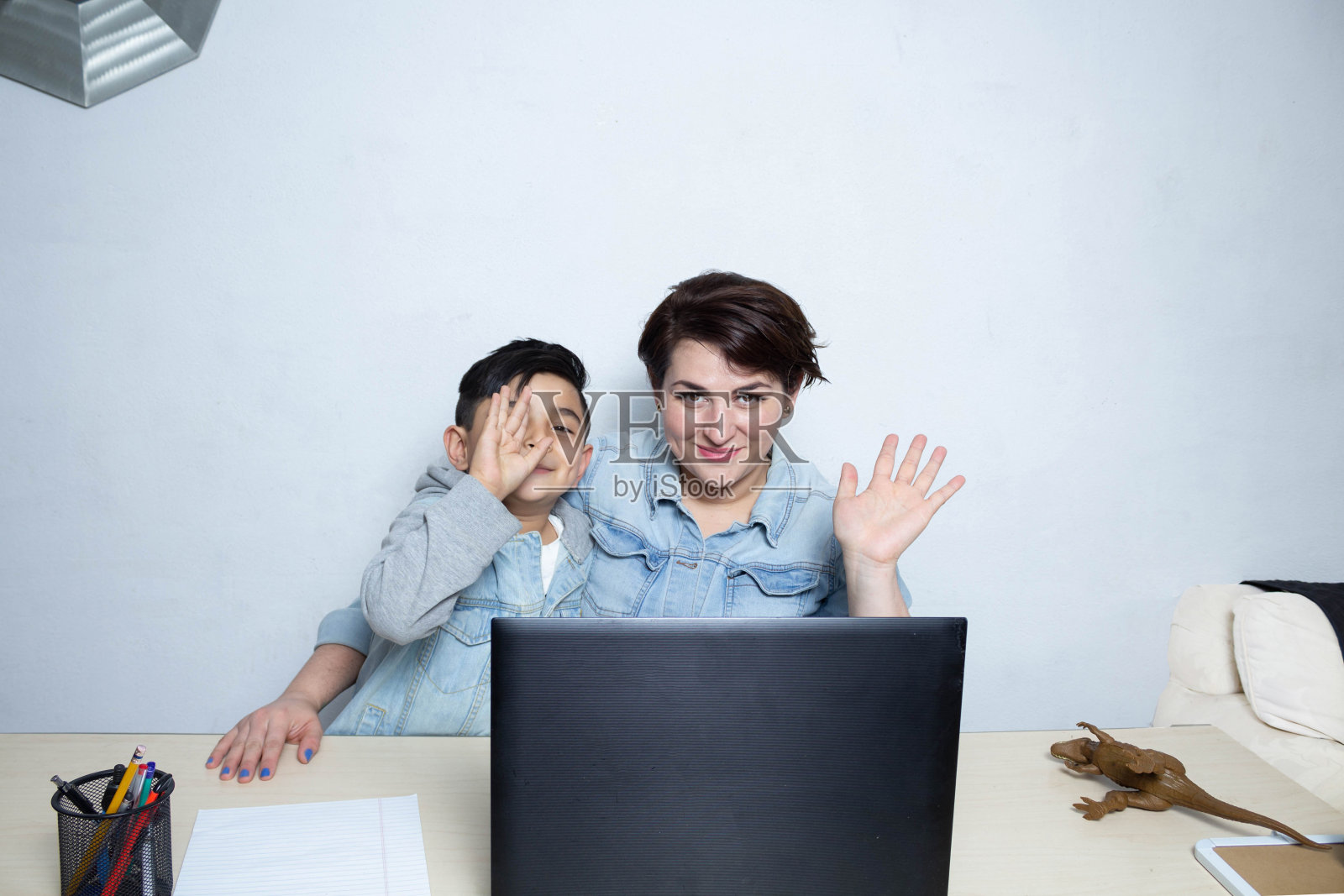 年轻的妈妈和儿子在视频通话前对着摄像机挥手。拉丁家庭照片摄影图片