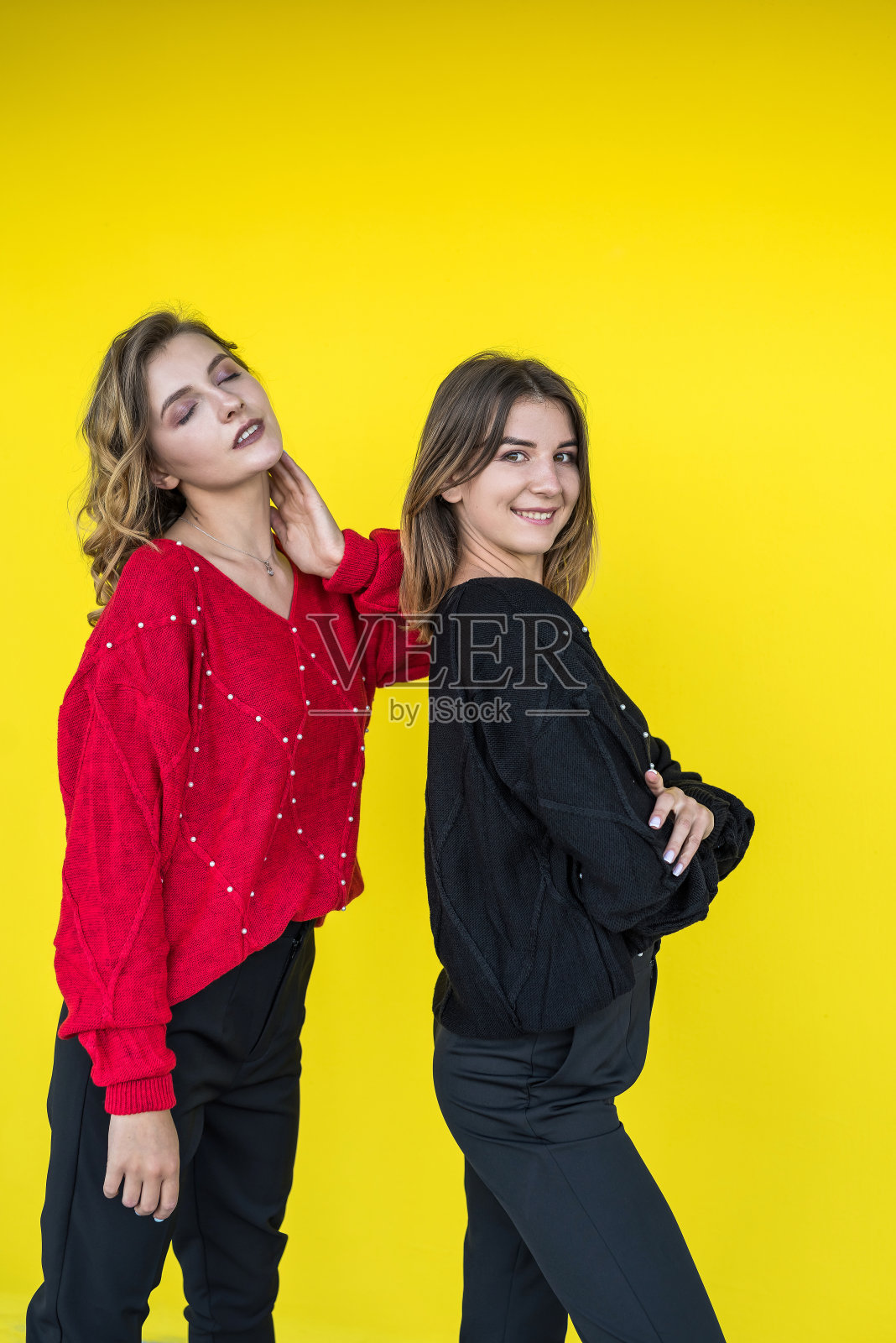 时尚女友穿着现代针织毛衣在黄色的墙上摆姿势照片摄影图片