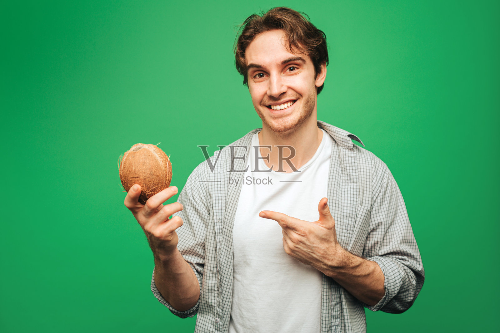 快乐的人捧着椰子,孤立在绿色的背景上照片摄影图片