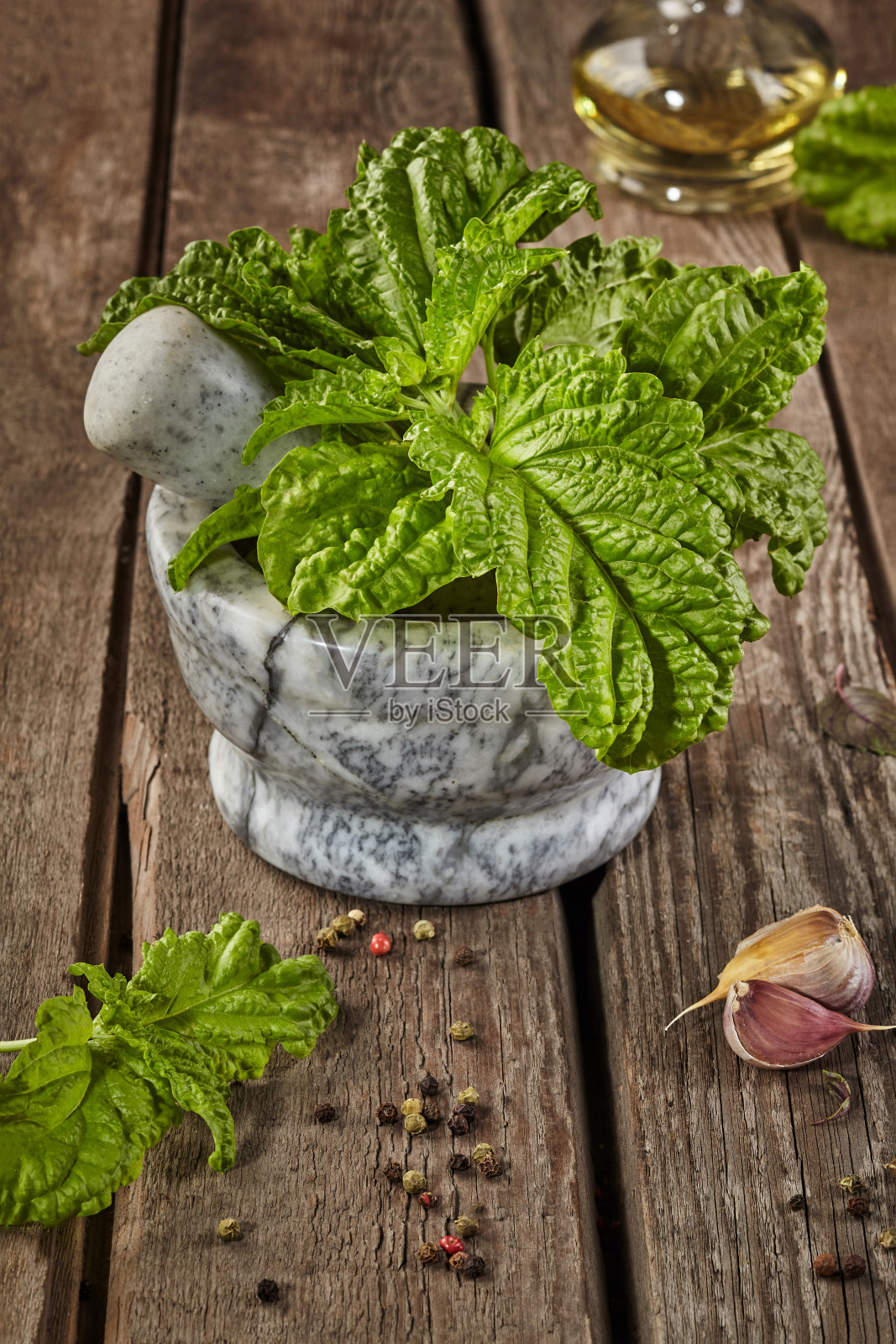 木桌上有石臼、罗勒卷叶和调味品照片摄影图片