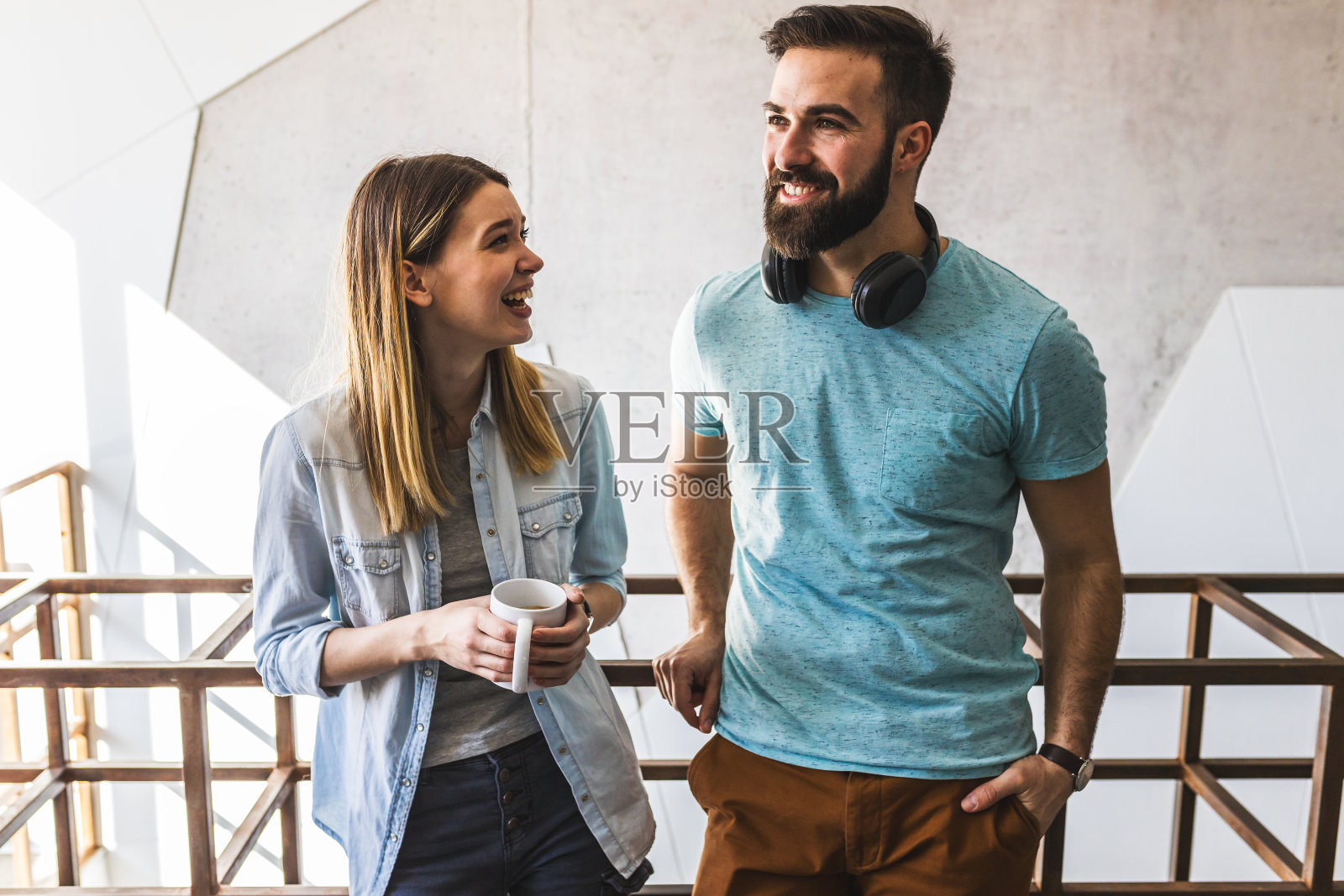 同事们站在大堂,聊天,享受咖啡休息时间。照片摄影图片