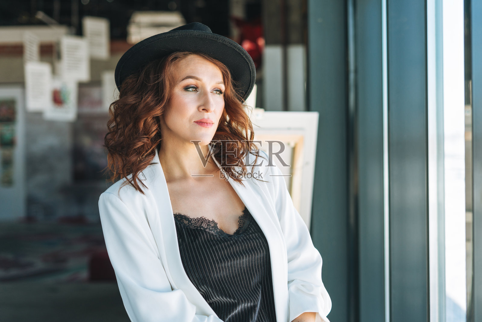 迷人的年轻女商人在黑色毡帽和白色西装参观现代艺术画廊展览照片摄影图片