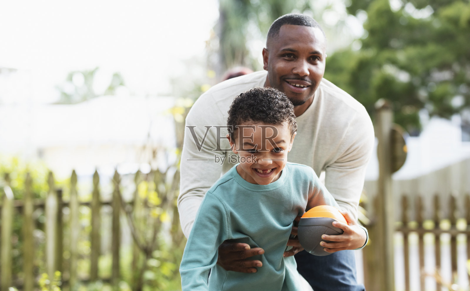 混血男孩和父亲在院子里玩足球照片摄影图片