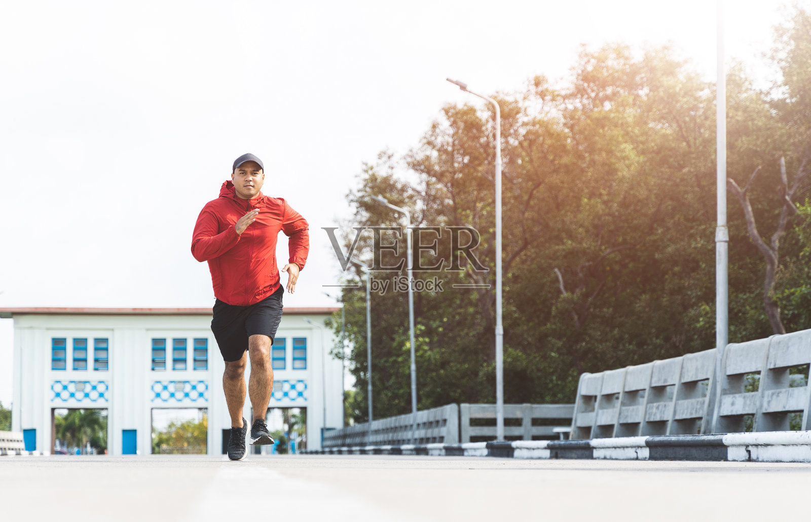 年轻的亚洲男子穿着运动服在户外跑步。印度人在路上慢跑的肖像。训练运动员户外运动的概念。照片摄影图片