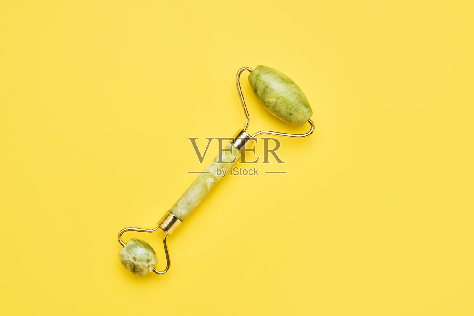 按摩辊脸部与两个玉石在黄色的背景。SPA,护肤理念照片摄影图片