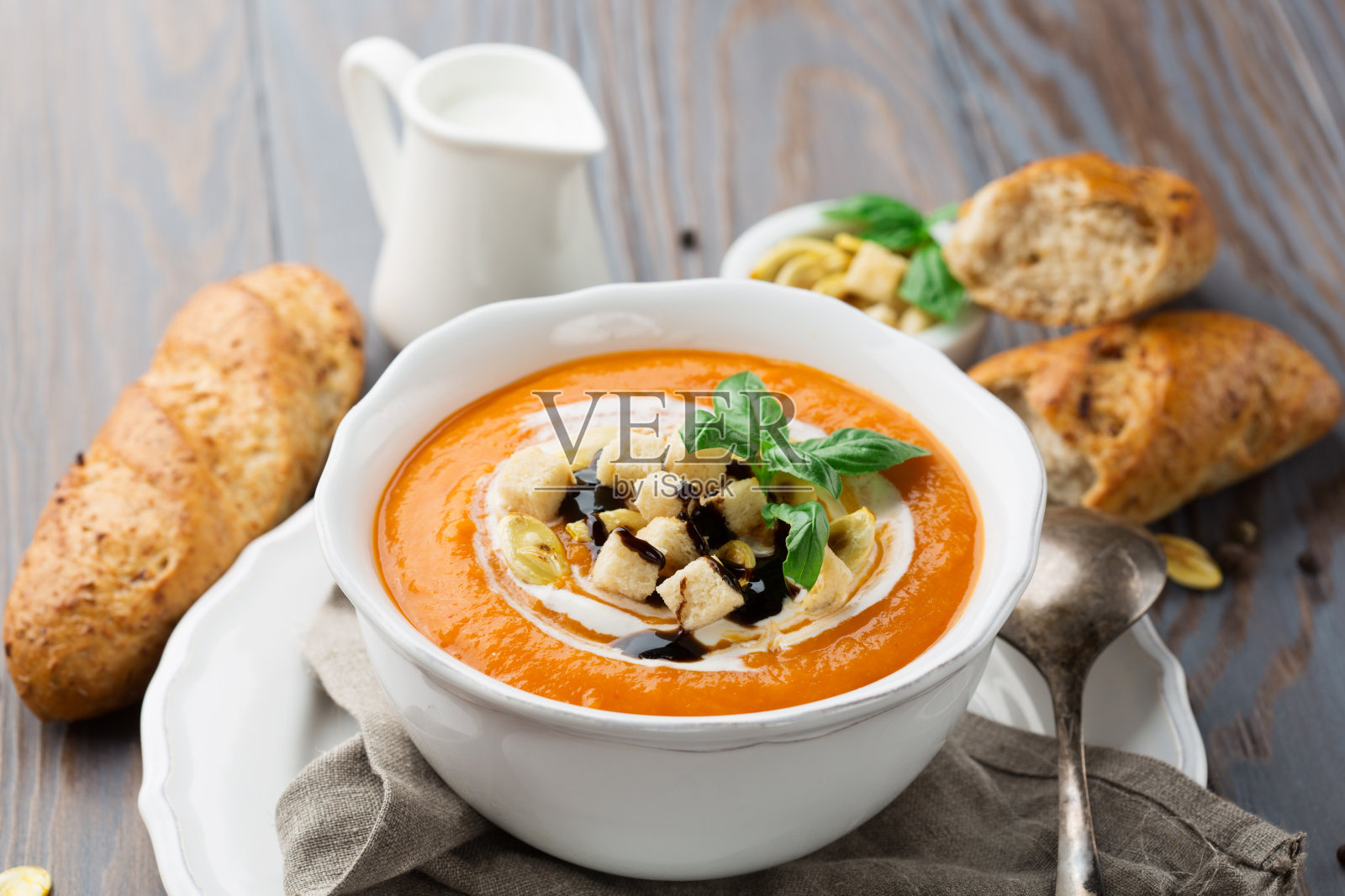 自制南瓜汤,奶油,面包丁和罗勒,背景是质朴的木头。照片摄影图片