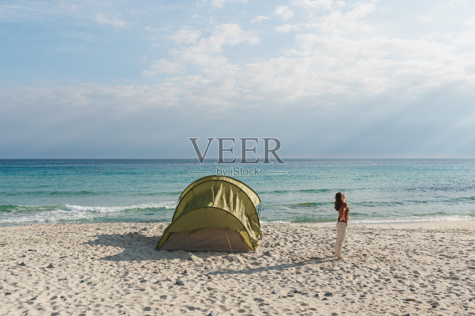 年轻女子背对着太阳站在海滩上呼吸新鲜空气照片摄影图片