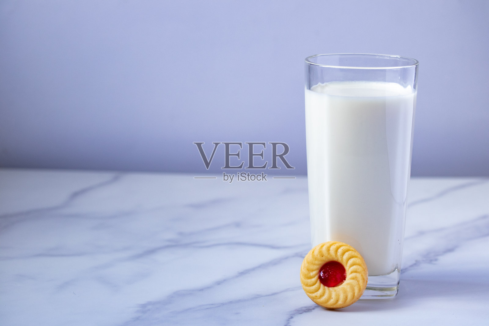 透明玻璃杯里的新鲜牛奶和白色背景上的草莓饼干照片摄影图片