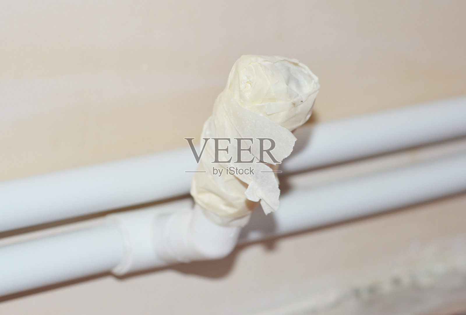 中央散热器加热管的阀门上的一个特写,周围包裹着遮蔽胶带,油漆工的胶带,以保持清洁从抹灰和装饰时。照片摄影图片