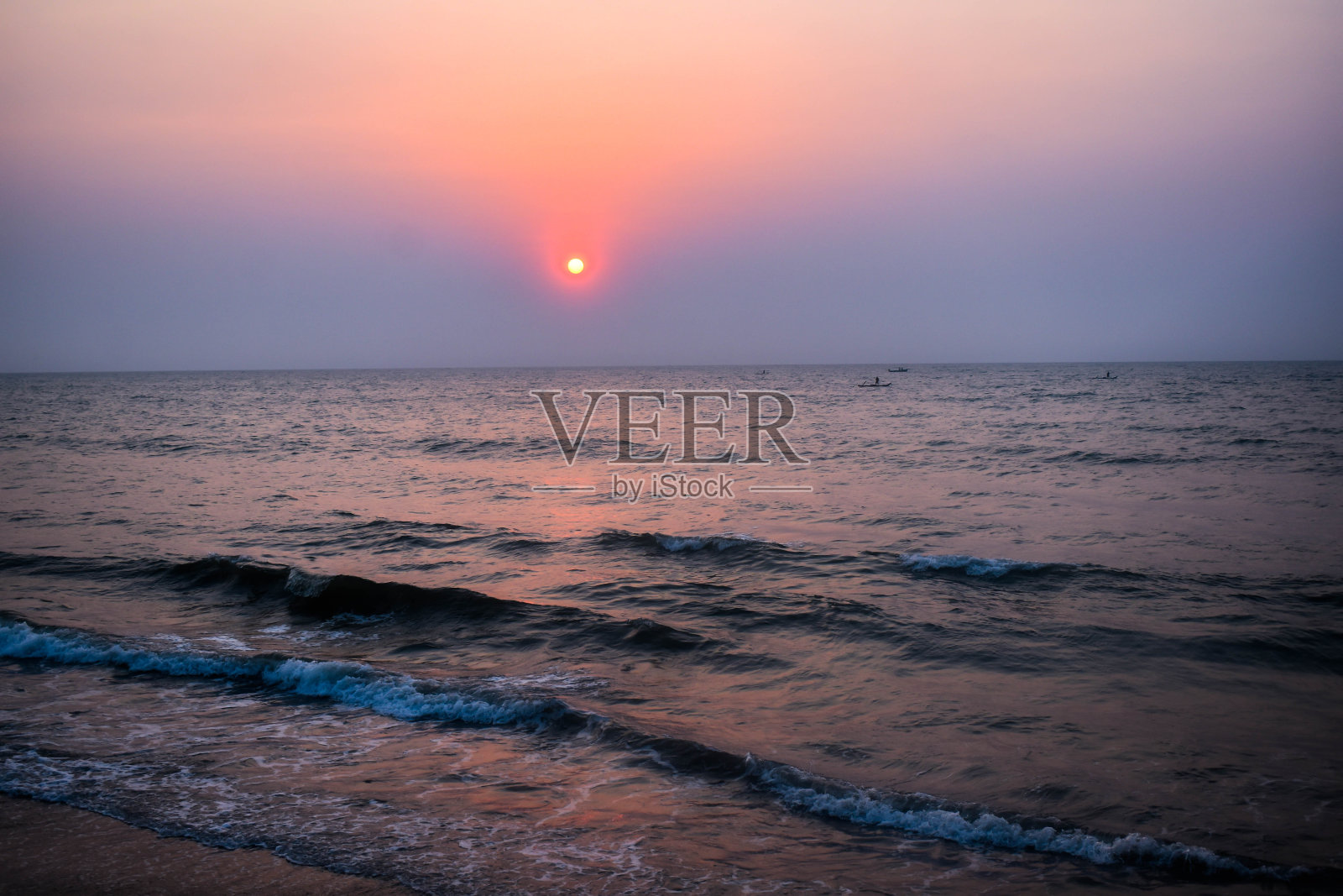 日出附近的海滩与船和波浪与闪光照耀他们照片摄影图片