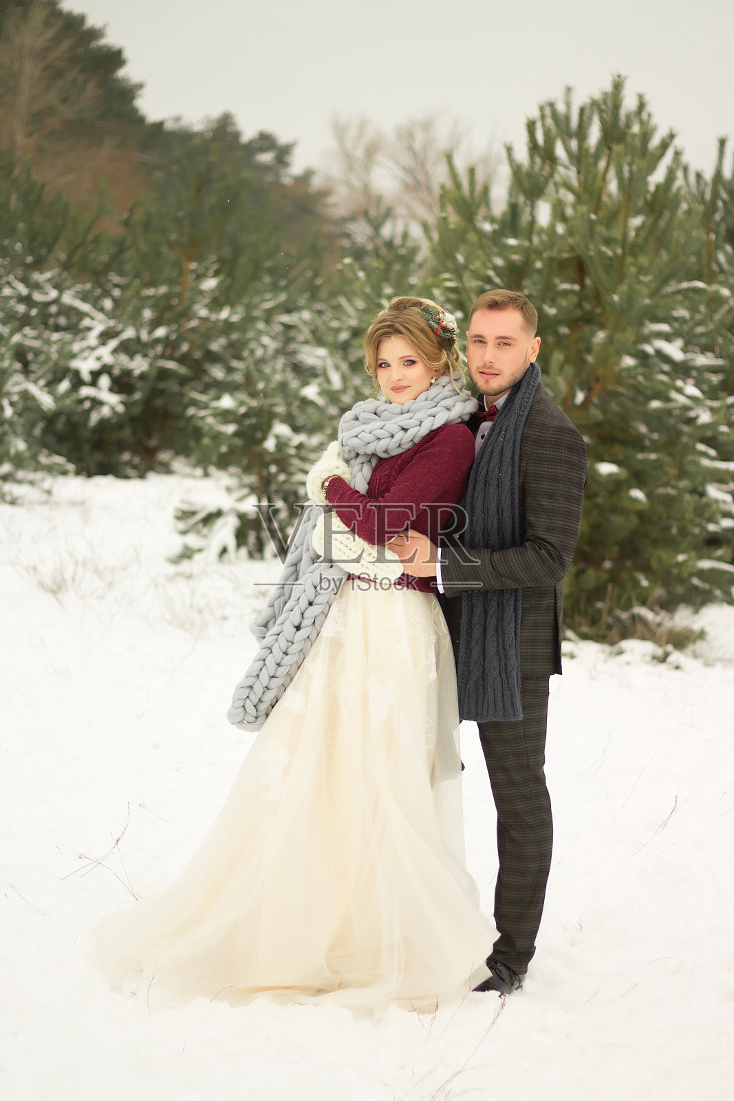 这对情侣拥抱着,亲吻着,手牵手,手里捧着一束花。有蝴蝶图案的套装,有裙子的外套。新娘和新郎照片摄影图片