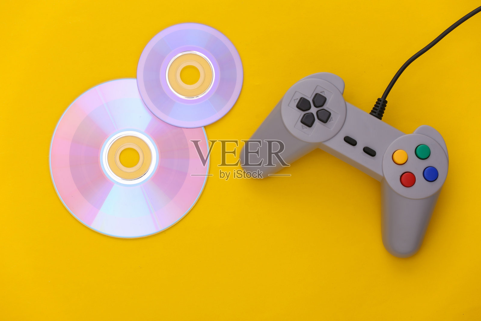 黄色背景的复古手柄和CD。游戏,电子游戏比赛。俯视图照片摄影图片