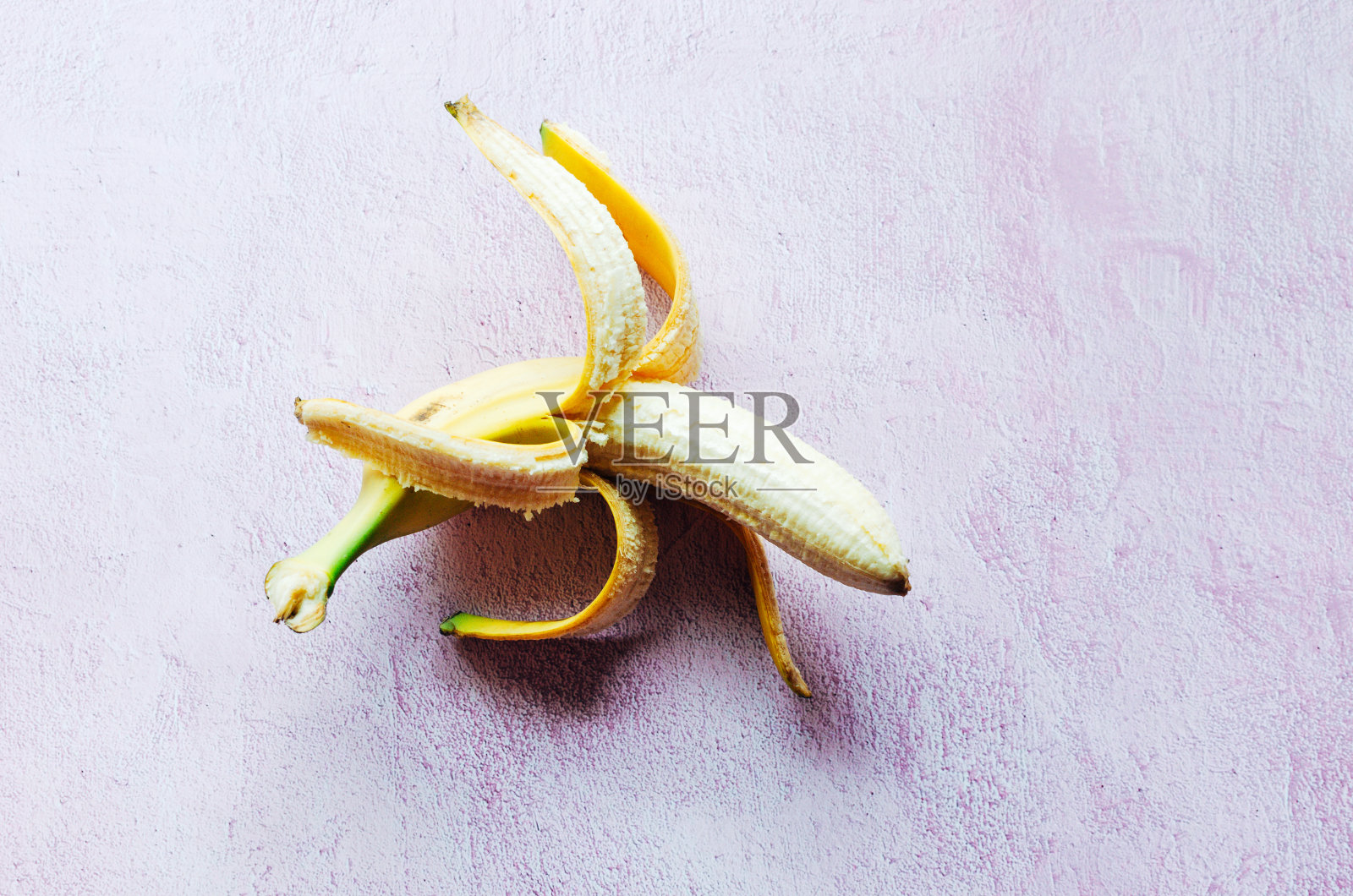 半开放的香蕉在粉红色纹理的背景照片摄影图片