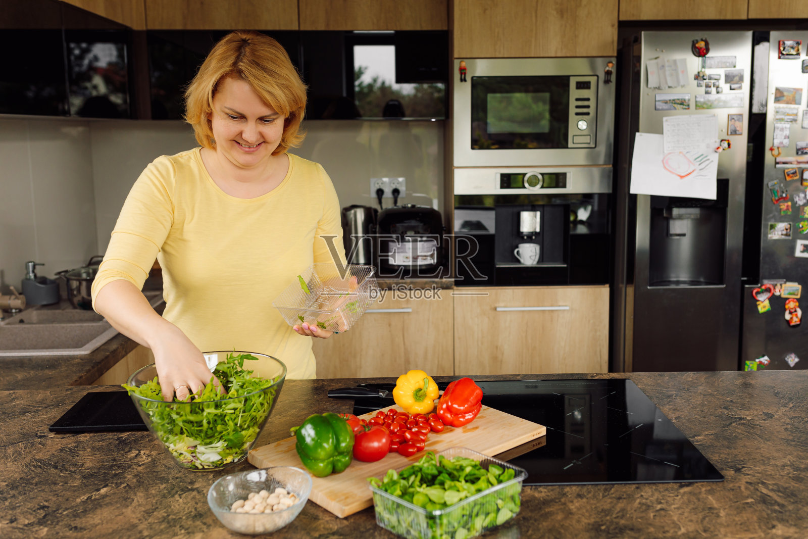 女人在厨房为她的家人准备新鲜蔬菜沙拉。健康和适当营养的概念。纯素食主义照片摄影图片