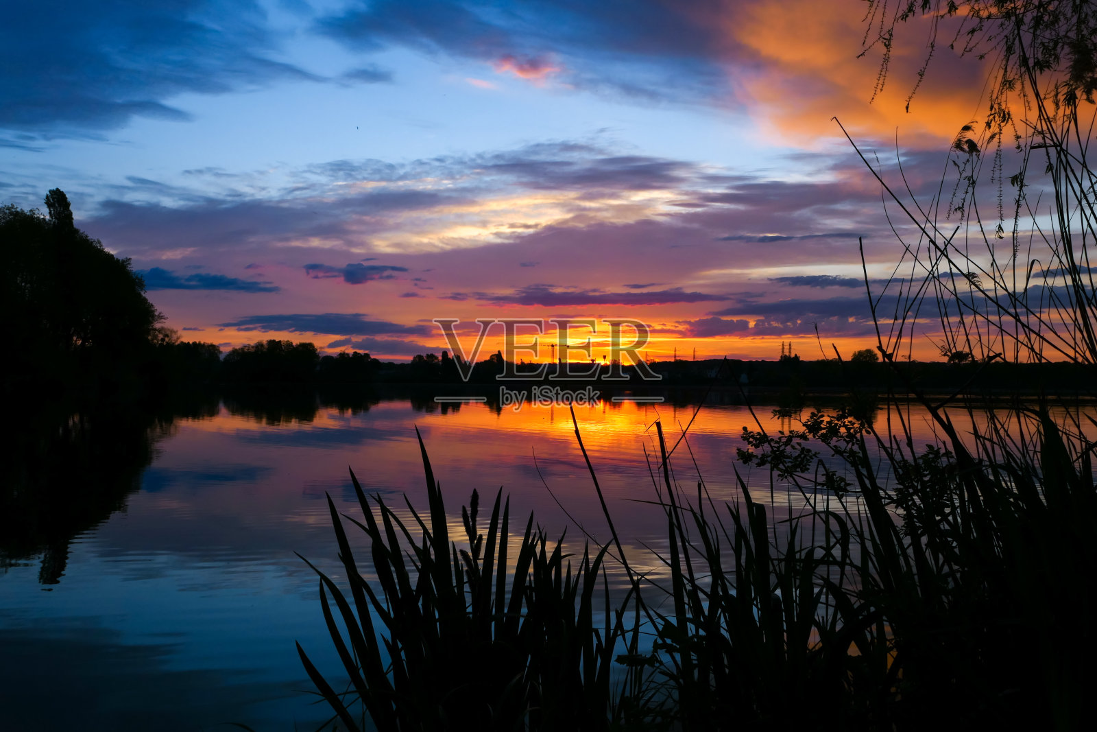 日出或日落的乡村景色与剪影的植被在一个湖。照片摄影图片