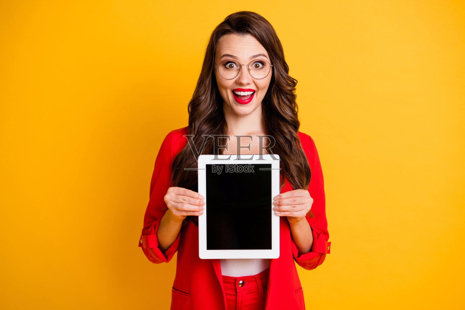 她的肖像,她漂亮,迷人,迷人,愉快,愉快,波浪头发的女士手握平板屏幕,新产品服务孤立在明亮,生动,闪亮,充满活力的黄色背景照片摄影图片