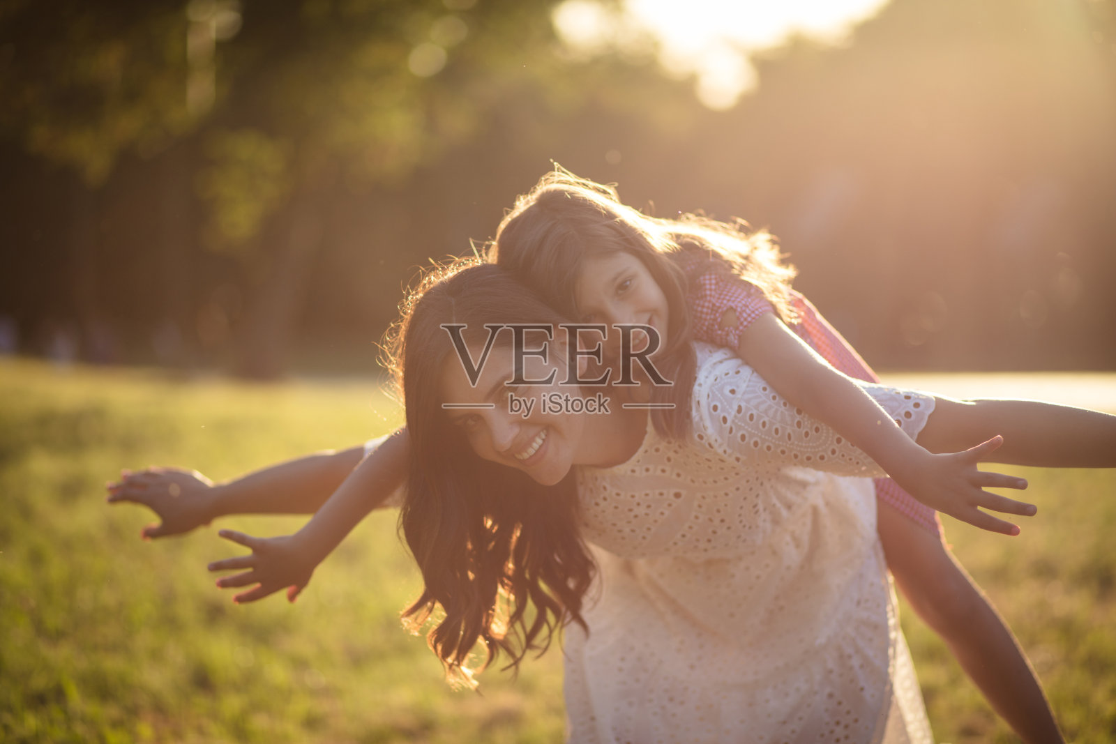 我们夏天的乐趣。母亲和女儿一起在大自然中玩耍。母亲背着女儿。照片摄影图片