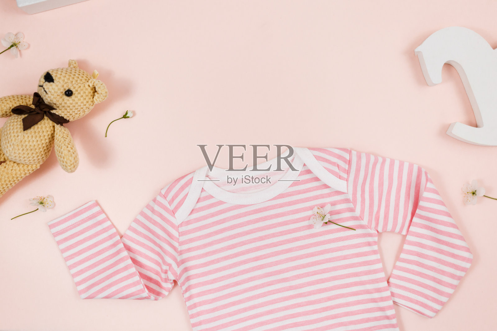 粉红色的桌子上放着新生男孩的粉色紧身衣、小熊和配件。有机棉婴儿紧身衣模型与环保木制玩具。宝宝送礼会,节日,生日装饰。俯视图照片摄影图片