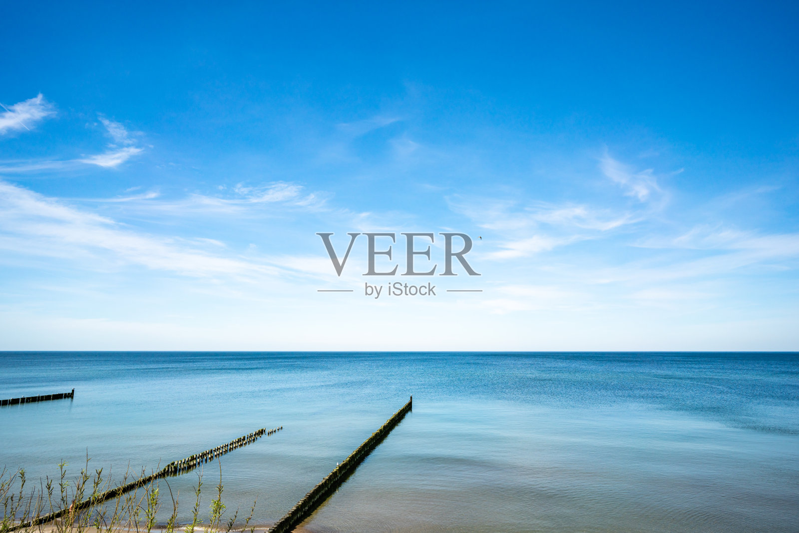 海滩的景色和一排防波堤在前景。照片摄影图片