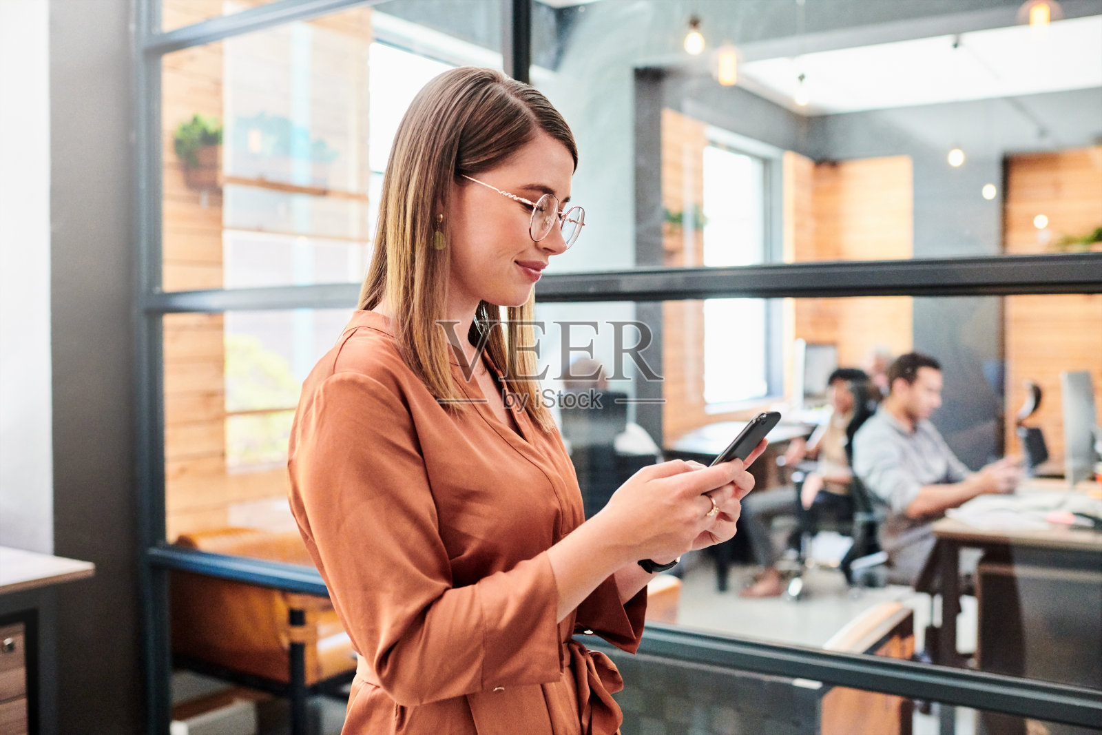 这是一个年轻的女商人在现代办公室里使用智能手机的照片照片摄影图片