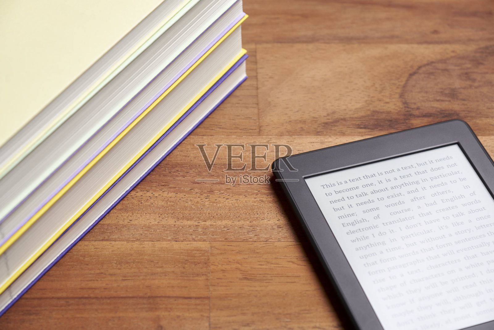 一堆书和电子阅读器上的文本屏幕上的木制表面照片摄影图片