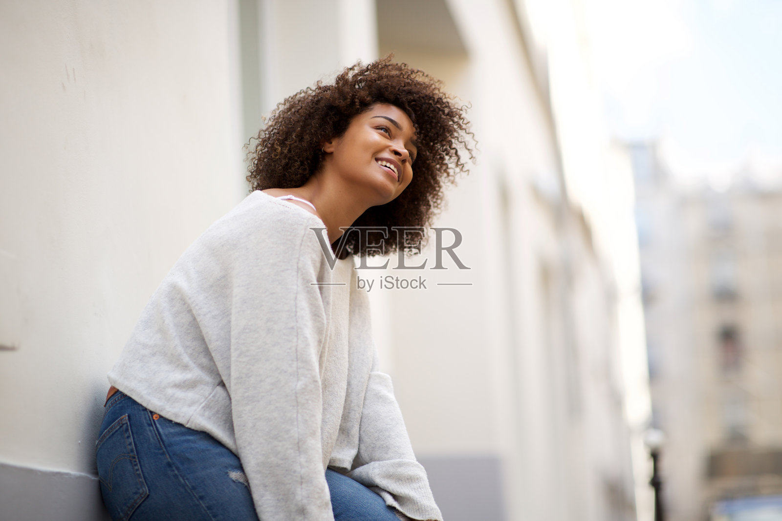 年轻的非洲裔美国妇女,靠在外面的墙上,看向别处照片摄影图片
