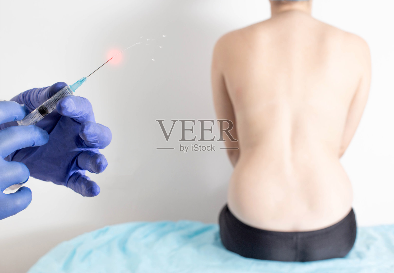 医生手持注射器,内含治疗背痛的消炎镇痛药物照片摄影图片