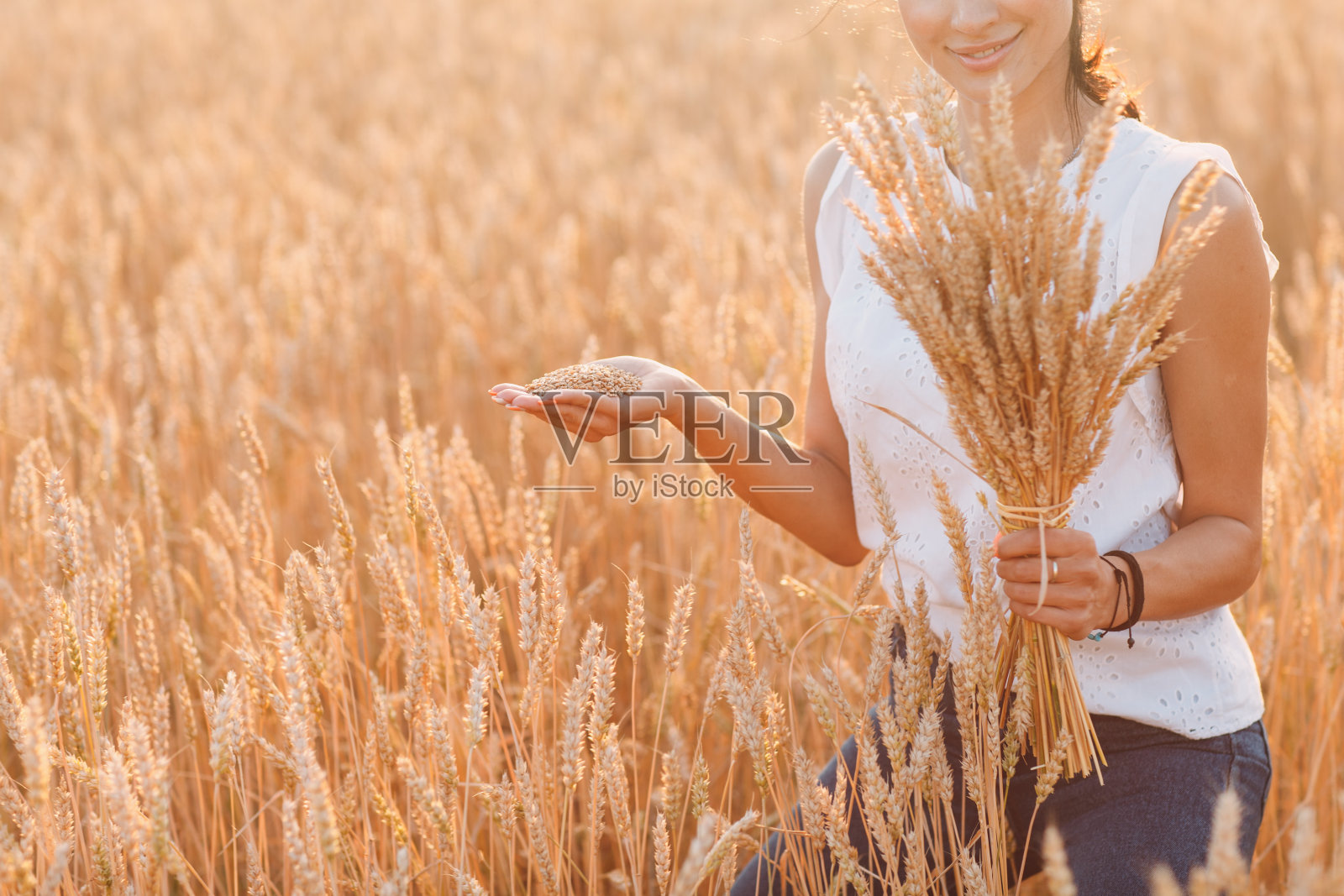农地里拿着麦穗捆的妇女照片摄影图片
