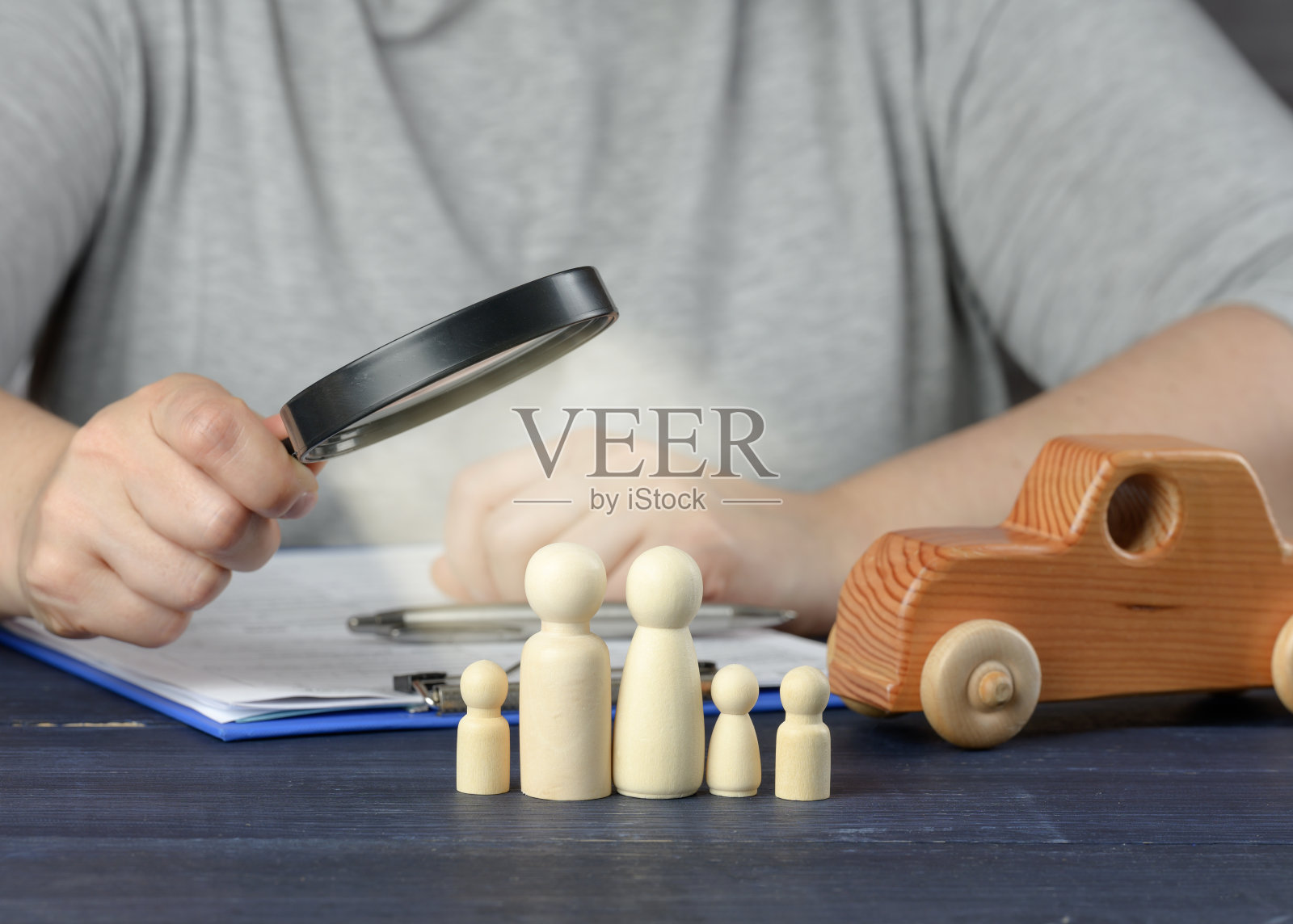 女性的手在放大镜中审视着家族的木雕。研究借款人信用历史的概念照片摄影图片