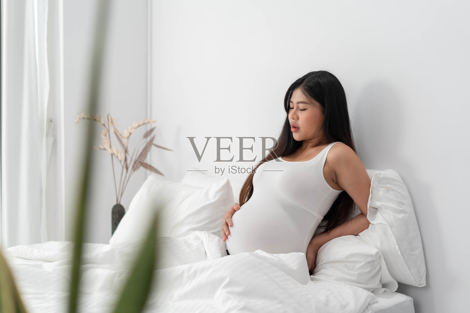 背痛的亚洲孕妇。美丽的孕妇摸着肚子,一只手放在背上照片摄影图片