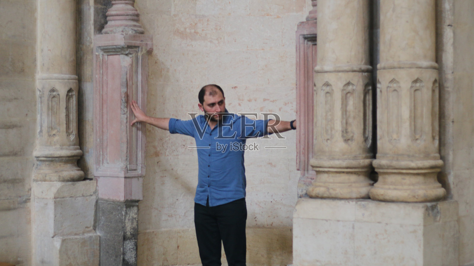 穿着蓝色衬衫的大胡子年轻人在封闭的纪念碑内环顾四周照片摄影图片