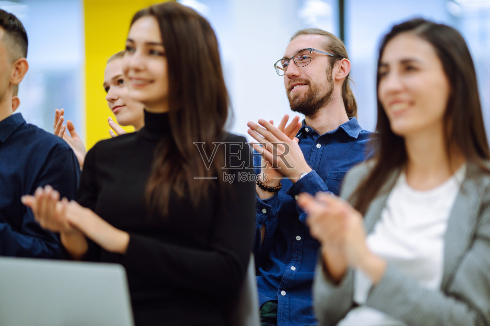 年轻的观众坐在一排,并做笔记,同时听报告厅。照片摄影图片