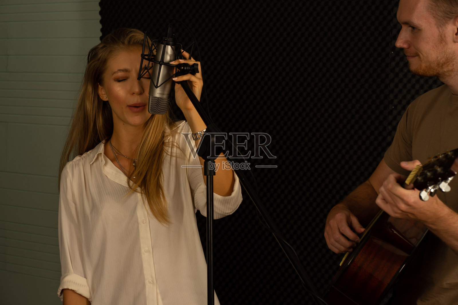 白种年轻美丽的歌手和男制作人在录音室照片摄影图片