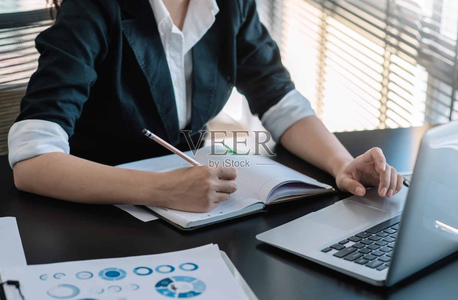 女商人通过在办公室做笔记和使用笔记本电脑来运用工作的概念。照片摄影图片