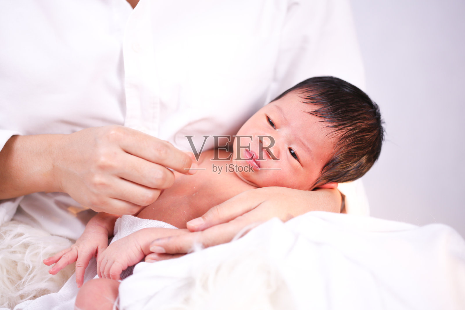 母亲把婴儿抱在膝上。宝宝和妈妈睡在一起。照片摄影图片